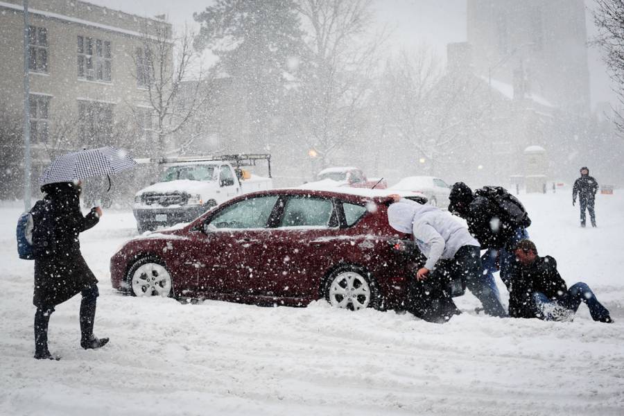 Students pushing car in snow