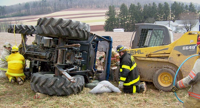 Firemen around a turned over tractor