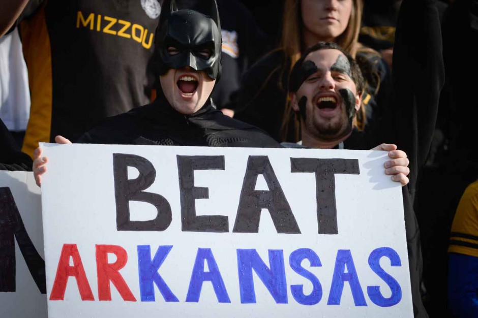 Fans in Batman costumes holding sign that says "Beat arKANSAS"