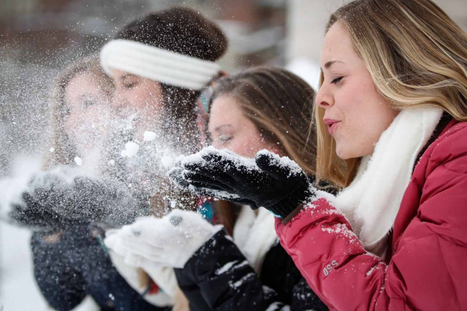 Ally Nuttall blows a handfull of snow into the air with her friends. Nuttall is a sophomore and spent part of her snowday playing in the snow before the snowball fight commenced. Photo by Hanna Yowell. 