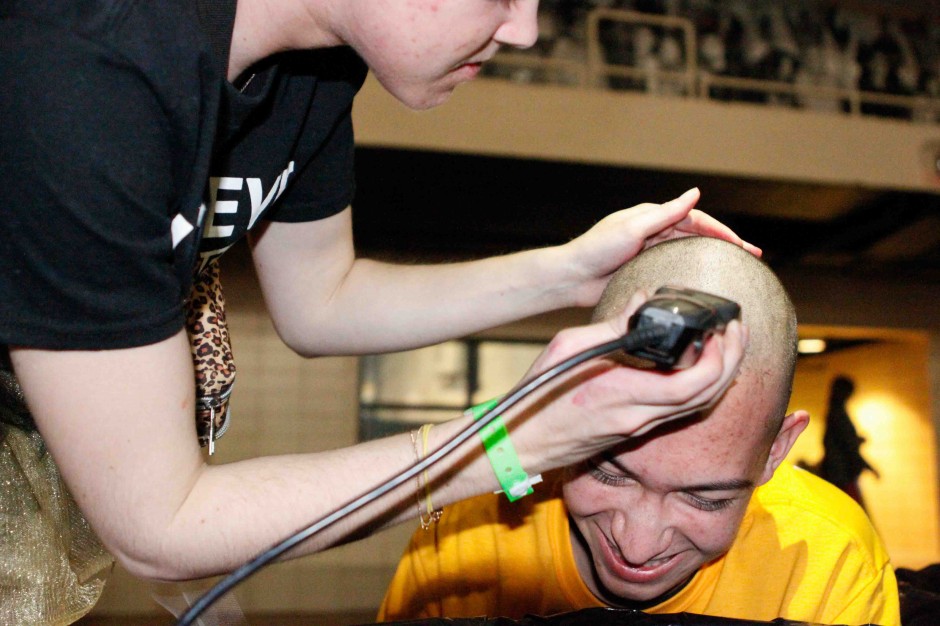 A hairdresser shaving a student's head.