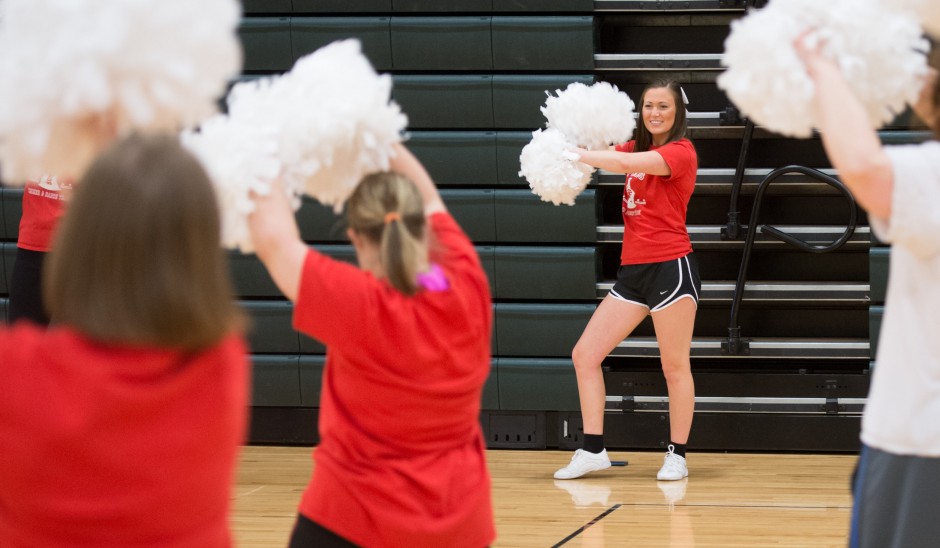Kelsey Boschert leading a cheer practice with pompoms.