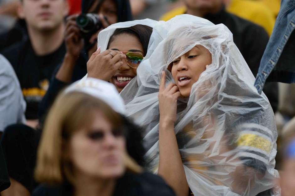 Shaina Thompson and River Bonds, freshmen, creatively share a single rain poncho as it starts to sprinkle near the end of the first half of the game.