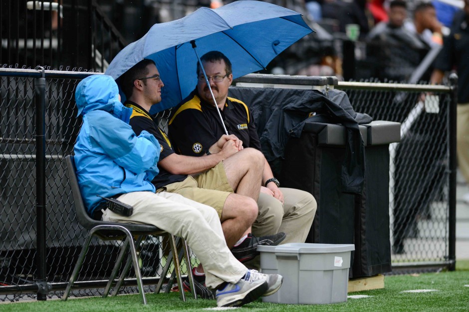 (From left to right): Joe Maddox, Scott Douglas and Chris Barron, members of the production crew, try to stay dry on the sidelines of Faurot field during the spring game.