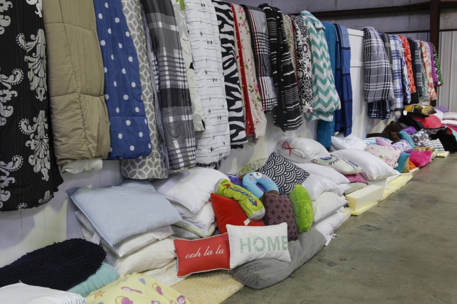 Comforters, blankets and pillows of all kinds lay against and on top of a white fence at Mizzou's surplus property warehouse in preparation for the Tiger Treasures Rummage Sale which will be held Saturday, May 30, 2015.