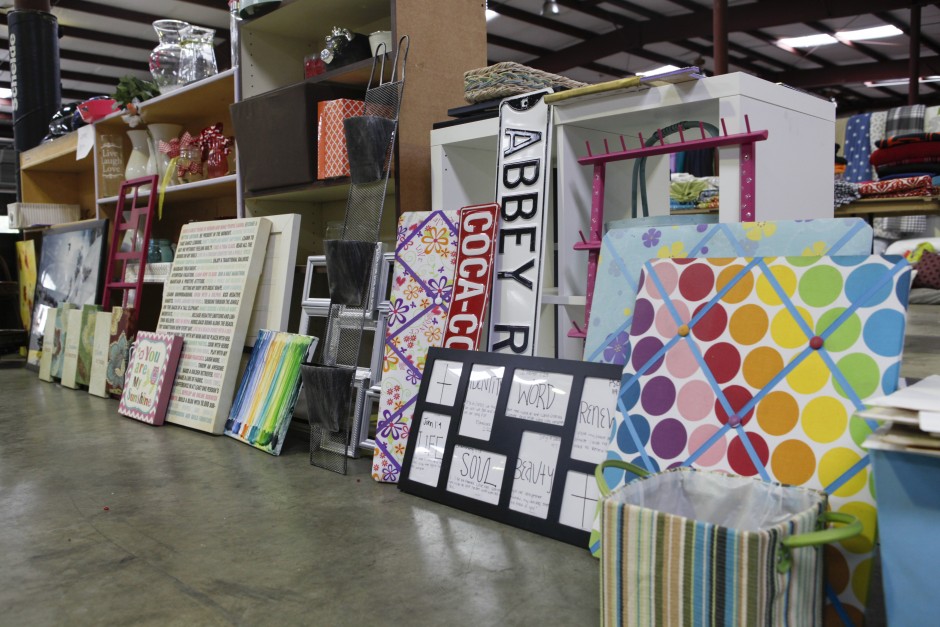 Picture frames, door signs, tack boards and more are assembled around shelves and desk furniture in preparation for the Tiger Treasures Rummage Sale in the warehouse of Mizzou's surplus property.