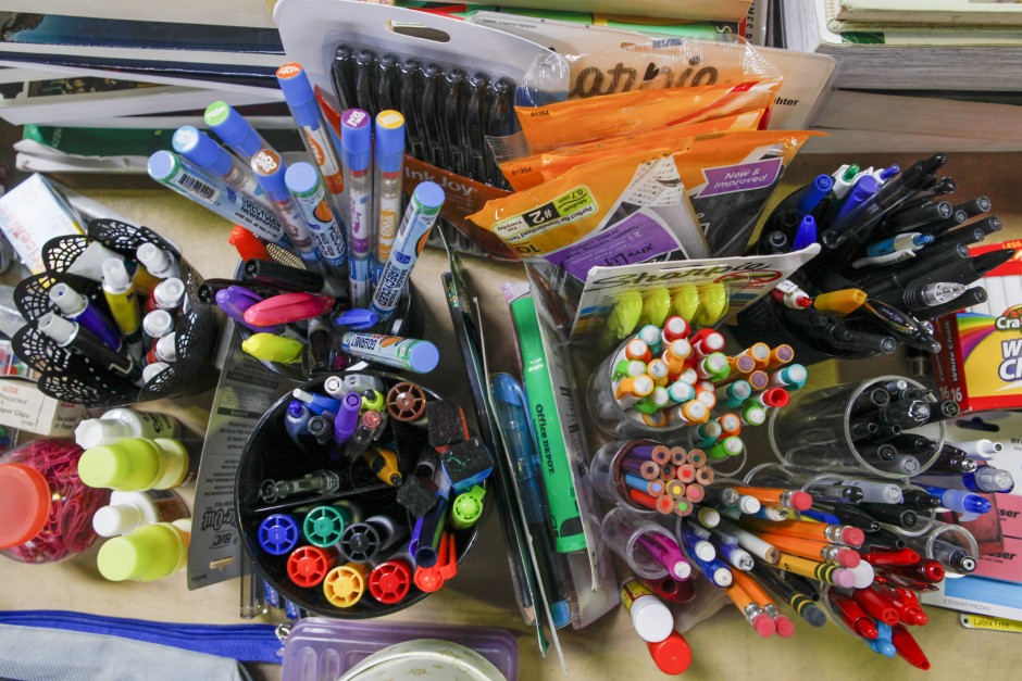 Pens, pencils, Sharpie markers and erasers are organized in pencil holders alongside notebook paper and other desk supplies in preparation for the Tiger Treasures Rummage Sale which will be held on Saturday May 30, 2015.