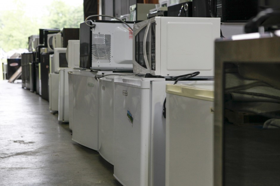 Mini-refrigerators sit underneath microwaves by a loading dock area in Mizzou's surplus property warehouse on Wednesday, May 20, 2015.