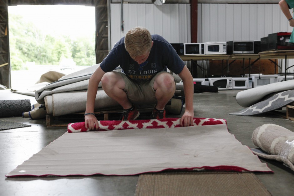 Dan Meyer, a senior education major, begins to roll up a rug before adding it to the pile of other rugs that will be for sale during the Tiger Treasures Rummage Sale on Saturday, May 30, 2015. "The most rewarding part is the end goal - kids going to camp!" Meyer said. Money raised during the rummage sale will be used as scholarship funds for families looking to send their children to the YMCA's Camp Mudd who need help paying for the $140 per week fee.