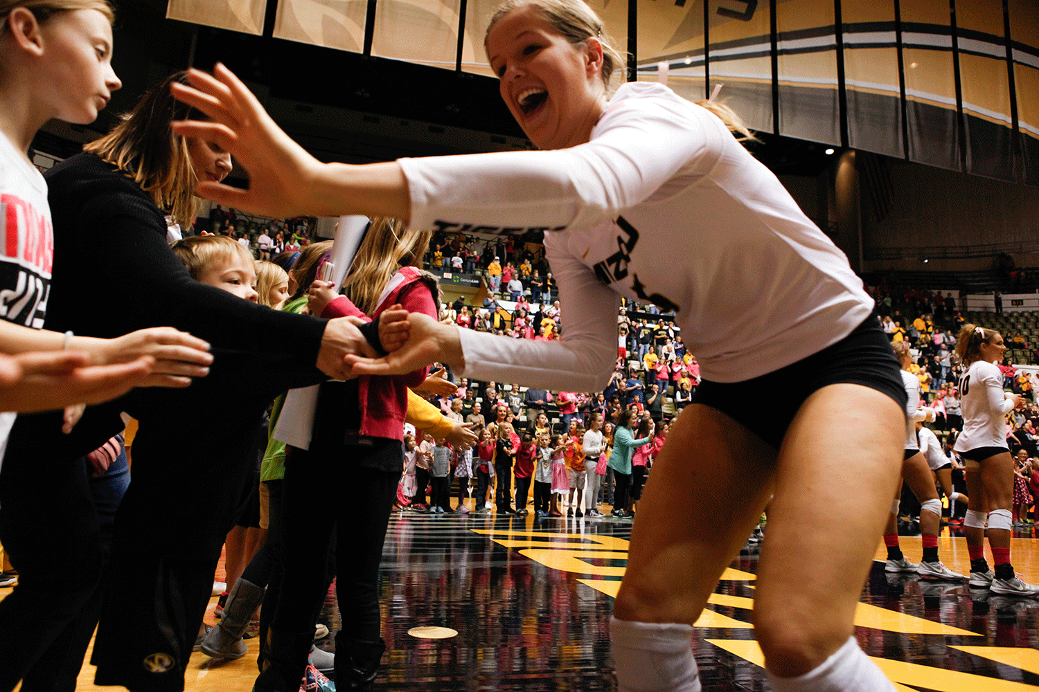 Ali Krecklow, Mizzou's sophomore setter, runs around the edge of the court, giving high fives to small Tiger fans before the match.