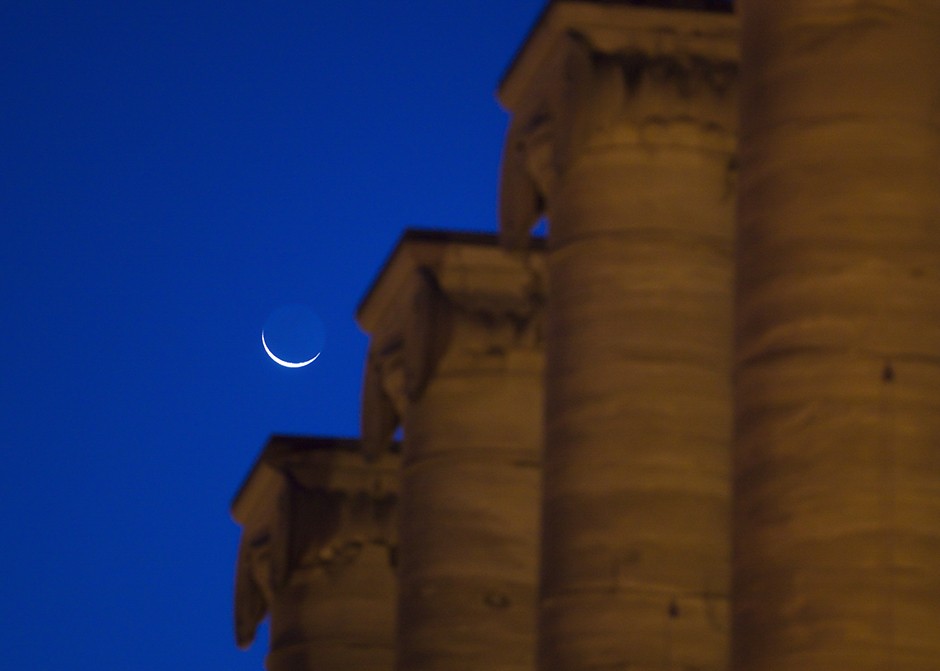 A crescent moon sets over the columns