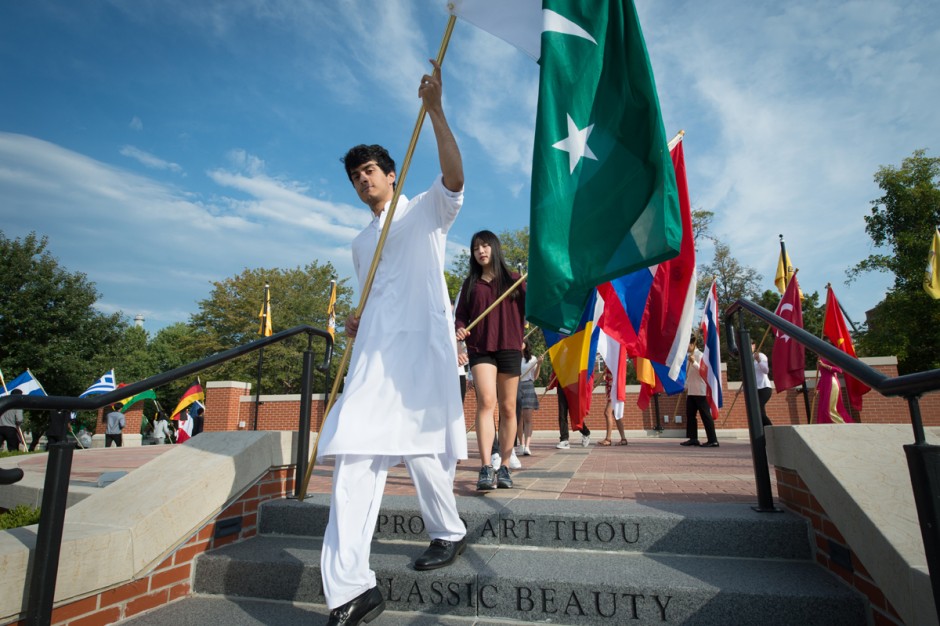 Students walking down stairs while carrying flags.