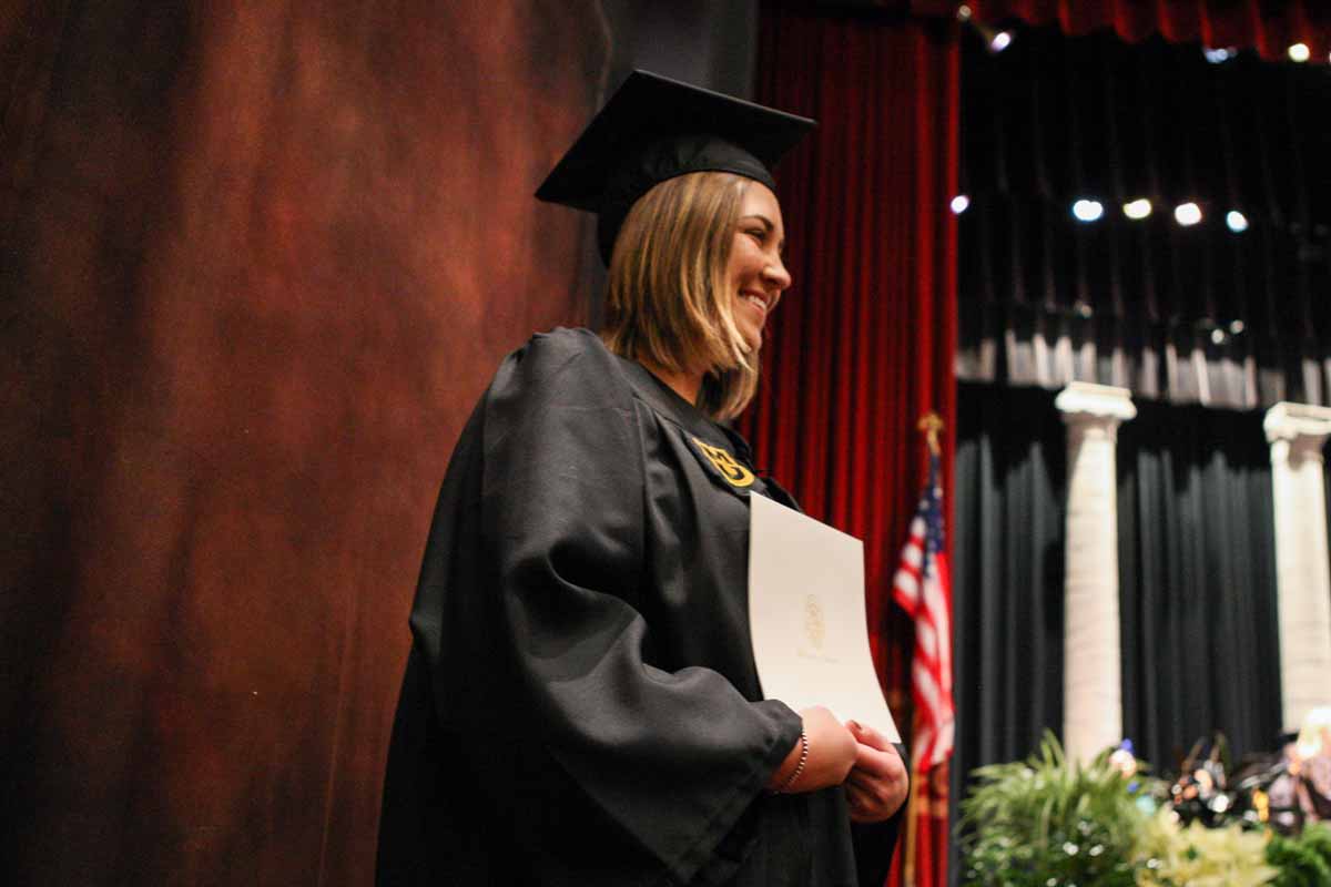 Devon Moltzan poses for a professional portrait with her diploma cover after walking off the stage in Jesse Auditorium Friday afternoon. Moltzan received a bachelors of science-human environmental sciences degree in family and consumer science education.