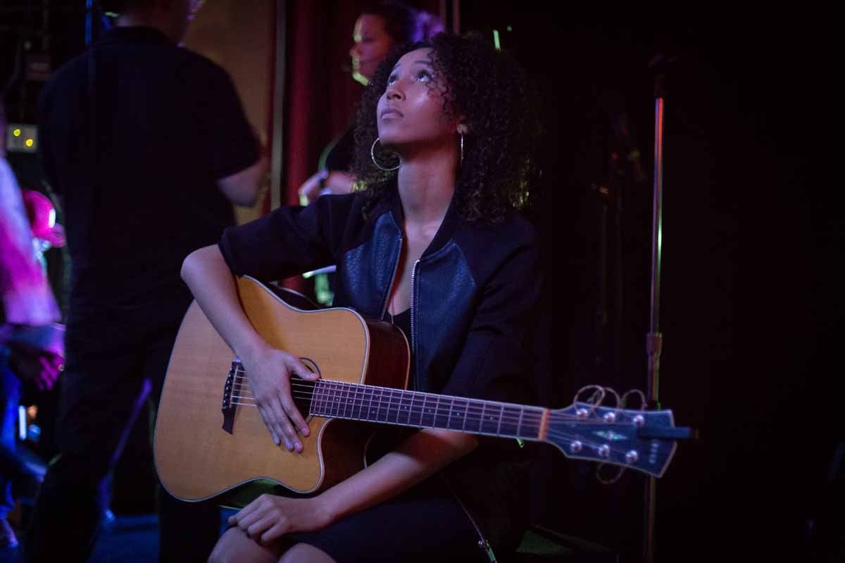 Mizzou Idol contestant Jhaere Mitchell sits backstage with her guitar waiting to perform her first song of the night during the semifinal round. Photo by Jake Hamilton. 