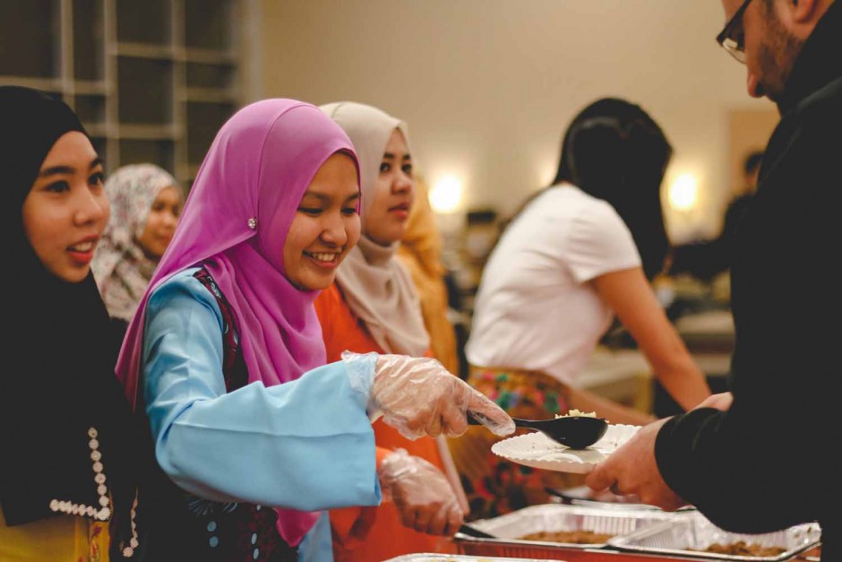 Nisa Ismail, member of the Malaysian Student Association, serves food to an attendee of the International Welcome Party.