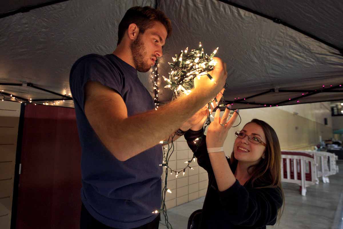 Preston Dynes and Alexis White, leadership members and morale captains for MizzouThon, detangle a string of Christmas lights to string up in a tent during set up Friday evening.