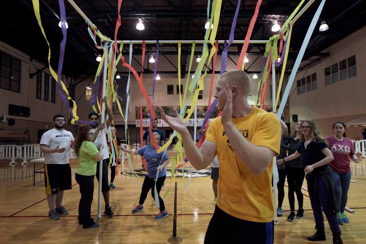 Senior Carson Miller, vice president of recruitment for MizzouThon, applauds as other leadership members help to erect the jail station after attaching streamers for decoration Friday evening.