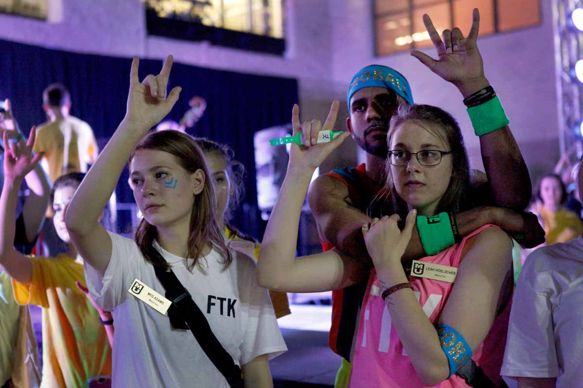 Meg Adams and Leah Hoelscher raise their hands in the air with the rest of MizzouThon leadership and dancers forming the sign language for "I love you" as Miracle Families cut wristbands off each dancer at the conclusion of the main event.