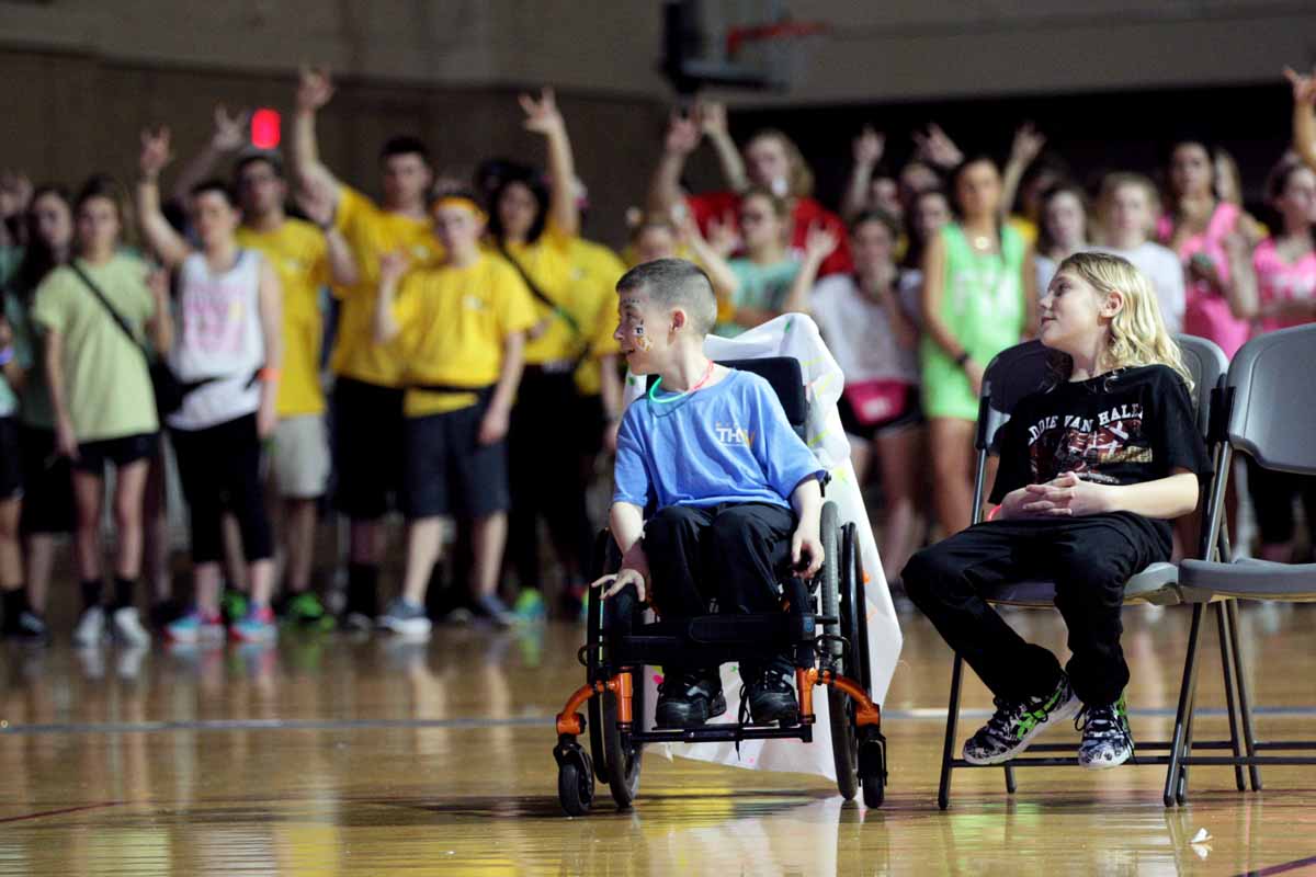 From left, Declan Johnson, 8, and Beau Edwards, 10, sit in the middle of a ring of dancers that just finished dancing 13.1 hours for them and other children like them.