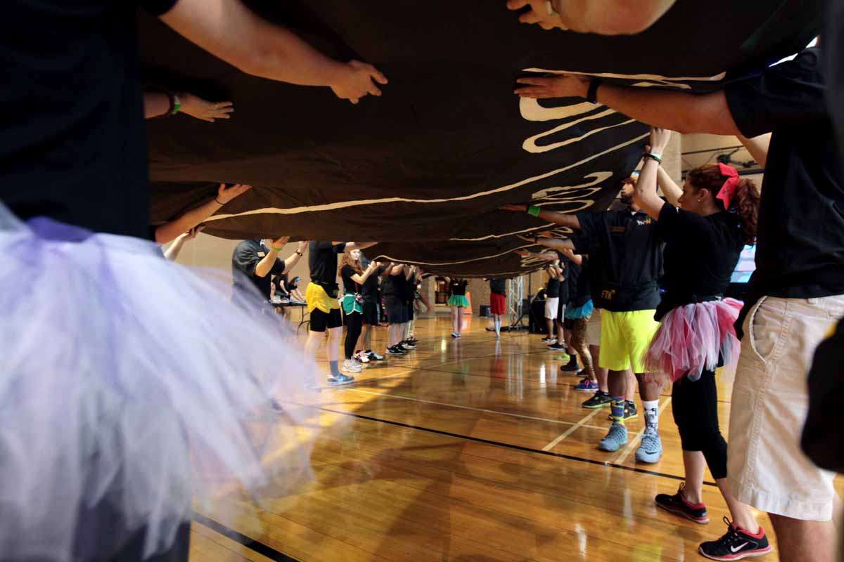 MizzouThon leadership members carefully carry a banner across the gym at the Mizzou Rec Center and over to a wall during set up Saturday morning, March 12, 2016. The banner allowed dancers to place a paper balloon under the amount of money they had raised.