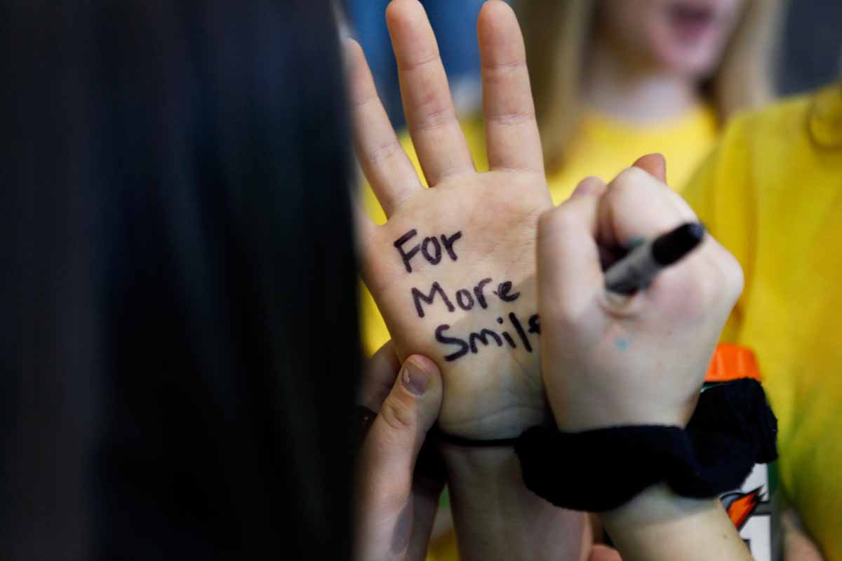 Sophomore Ann Marie Metzendorf, MizzouThon’s marketing strategist and morale captain, writes “For More Smiles” on sophomore Carina Cusumano’s hand upon arriving at the main event in Mizzou’s Rec Center Saturday morning. Dancers are encouraged to write why they dance on their hands and then pose for a photo for social media.