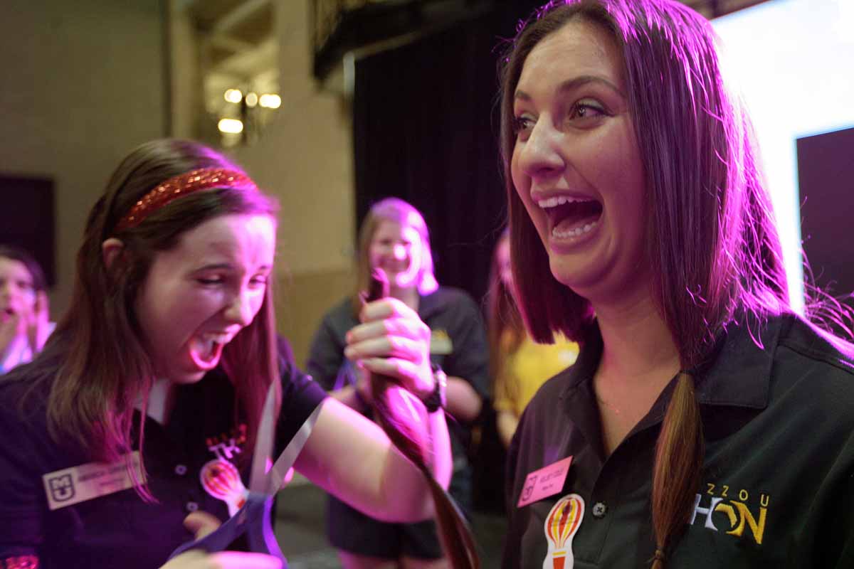 Senior Kelsey Cole, a leadership member for MizzouThon, reacts as senior Amanda Gingrich, also a leadership member, cuts off 20 inches of Cole's hair Saturday, March 12, 2016. The hair was donated to Children With Hair Loss.
