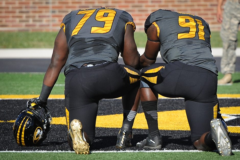 Defensive lineman Terry Beckner, Jr., left, and defensive lineman Charles Harris take a knee to pray before the game begins. Photo by Shane Epping.