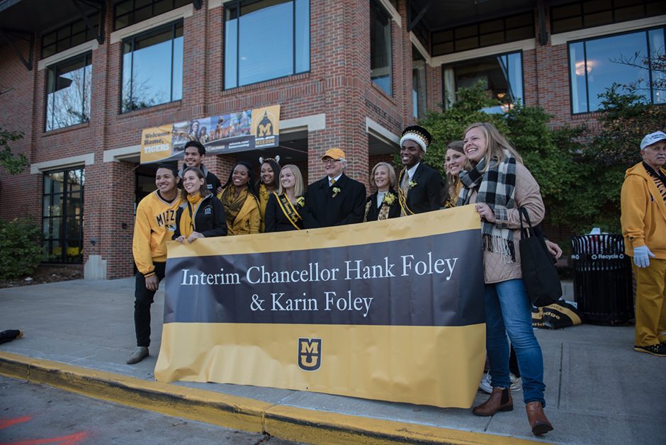 Students pose with the chancellor and his wife behind a banner.