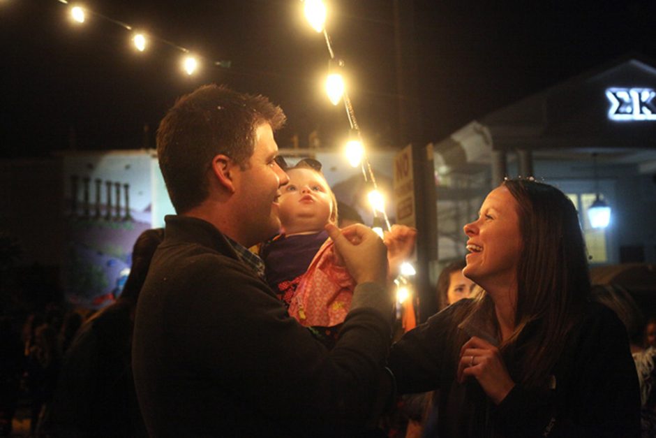 Mike Puricelli and Elizabeth Puricelli laugh as their 11-month-old daughter, Annalise Puricelli, is mesmorized by the Christmas lights hanging outside of Chi Omega sorority during the homecoming house decoration showcase on Friday, Oct. 22, 2016.