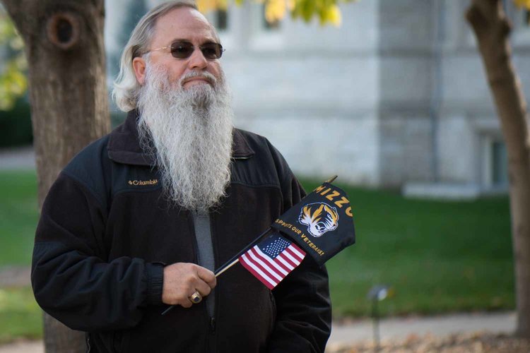 Man with grey beard holding flags.