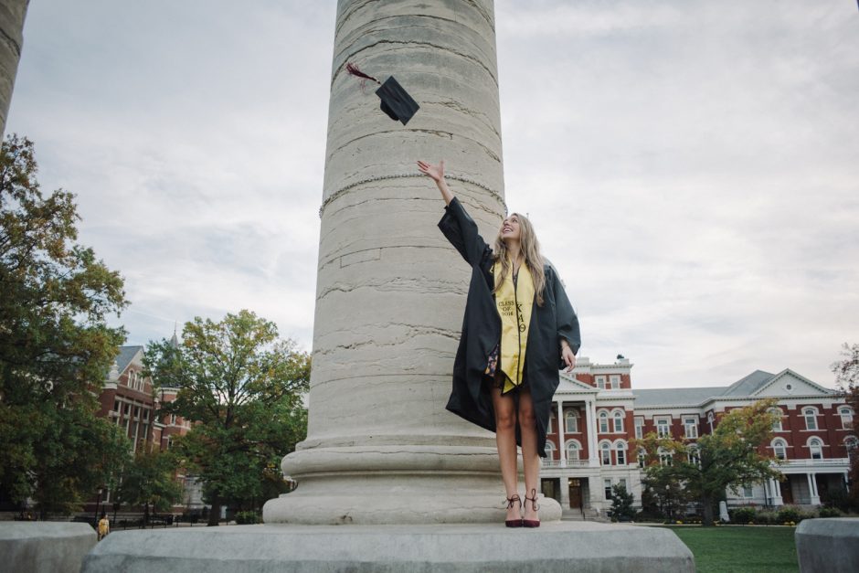 Becca Bogle tossing her cap into the air while standing at the base of a column