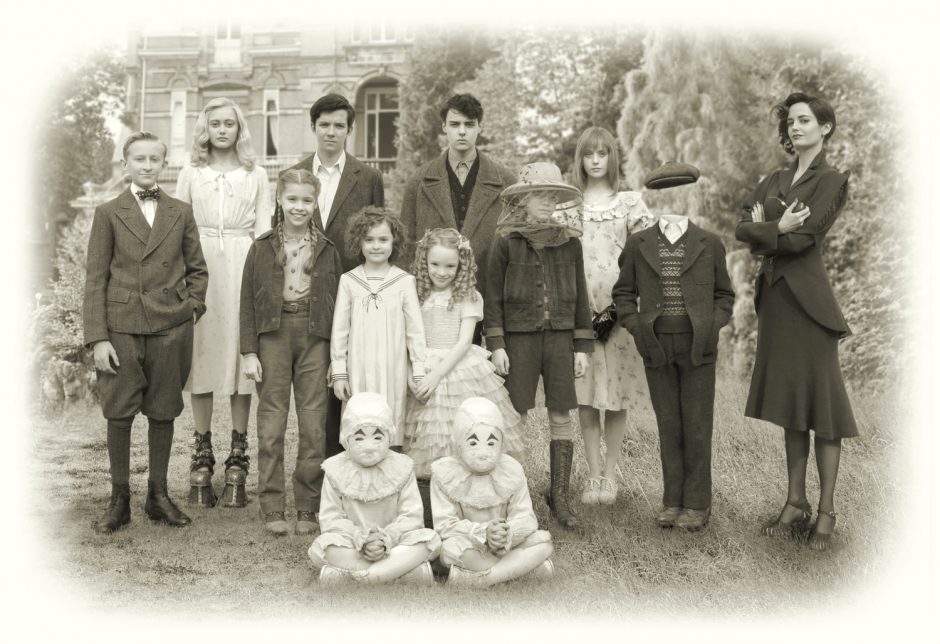 Old-timey photo showing a group of odd children in front of a house.