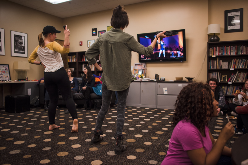 Students dancing in front of a video game screen.