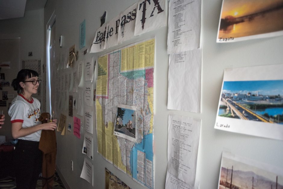 Student looking at maps, charts and other papers tacked to a wall.