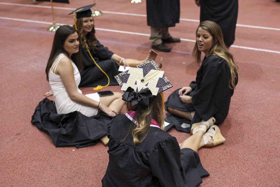 Women sitting on floor in caps and gowns.