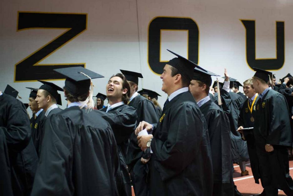 Students in caps and gowns walking together and laughing.