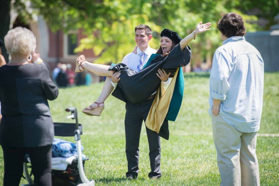 Man picking up woman in a cap and gown.