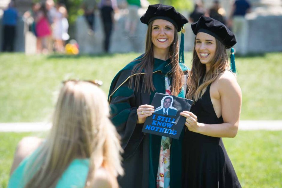 Two students holding cap that says "I still know nothing" with photo of Michael Scott from "The Office."