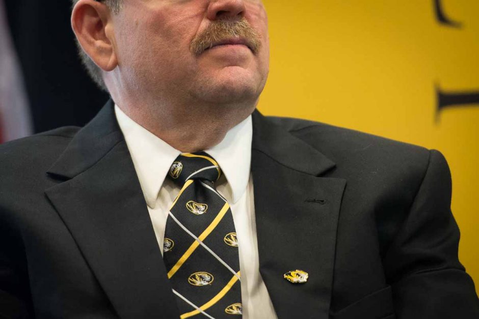 Chancellor Alex Cartwright sports a black and gold tie and lapel pin.