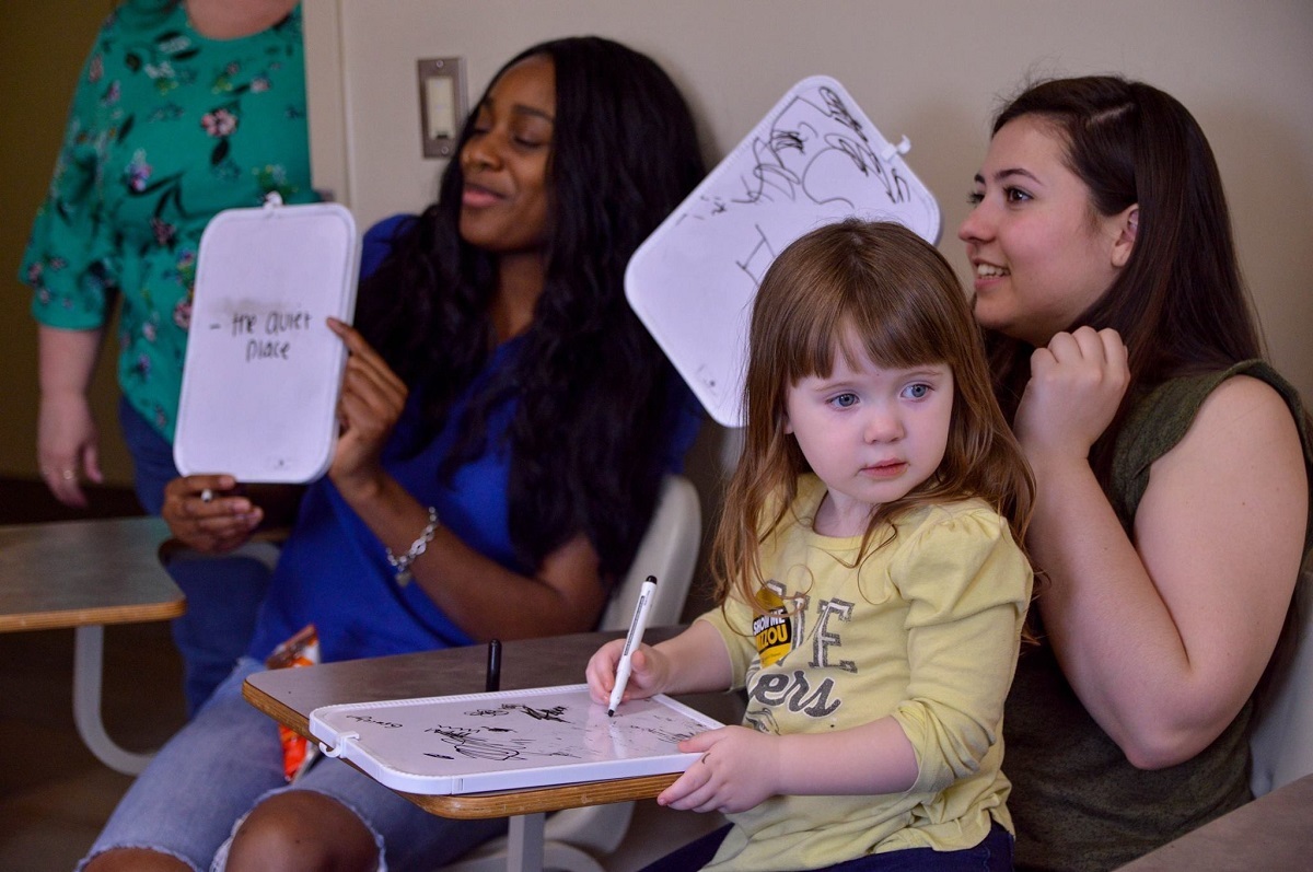 Two women and a young child participate in a whiteboard activity during Show Me Mizzou Day. 