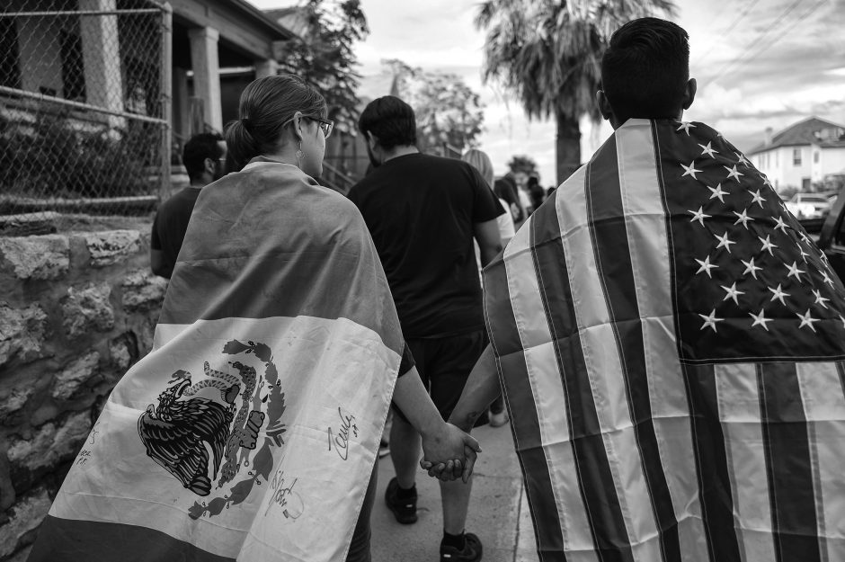 Hundreds of people, including a couple draped in Mexican and American flags, marched through central El Paso on August 2, 2019 in a protest against gun violence, in the wake of the Walmart terrorist attack. The Latino communities of El Paso and Ciudad Juarez were horrified to learn that the killer, who gave himself up for arrest, was specifically targeting Latinos and drove 600 miles to the Walmart where he gunned down scores of shoppers, killing 22.